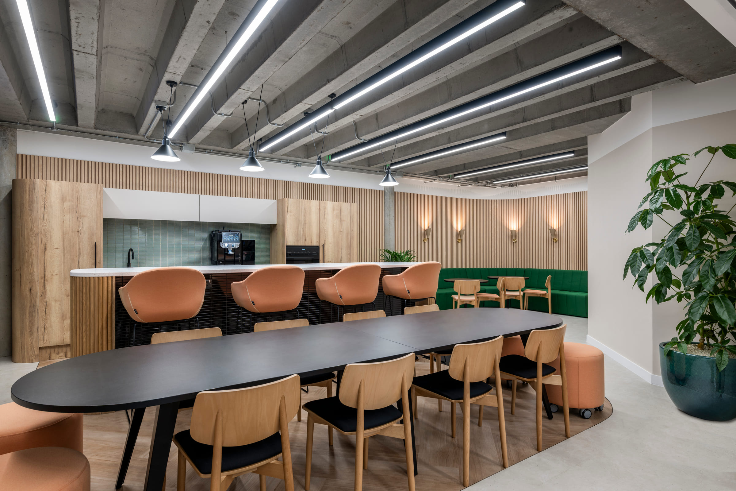 Tea point with long oval table, timber cladding and green banquette