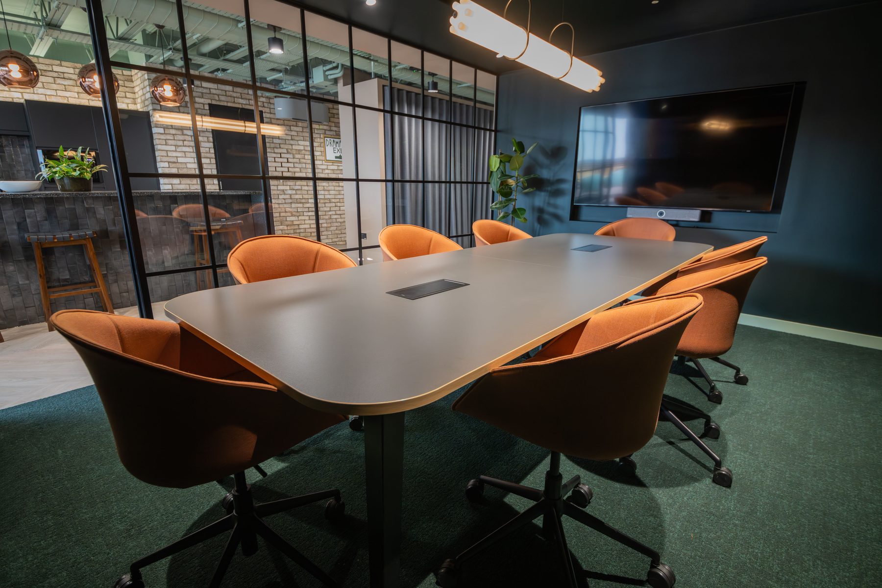 Coda HQ meeting room with dark green walls, salmon chairs and green carpet