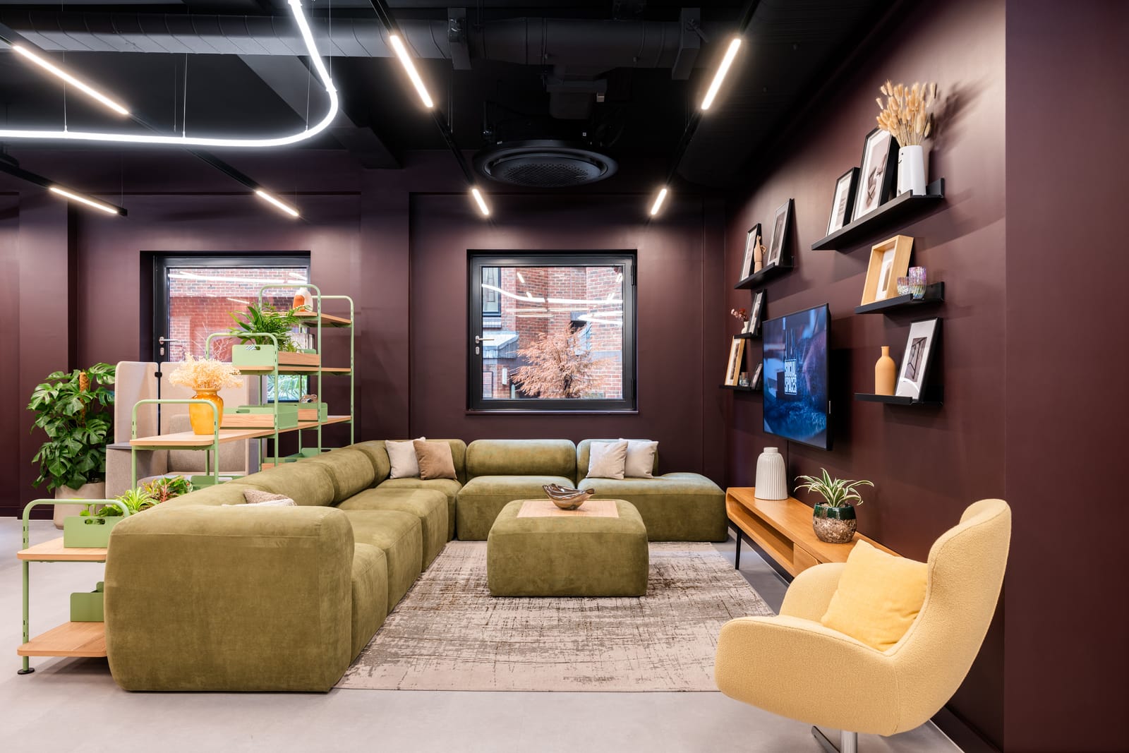 Lower ground lounge with olive modular sofa, mustard armchair and floating display shelves