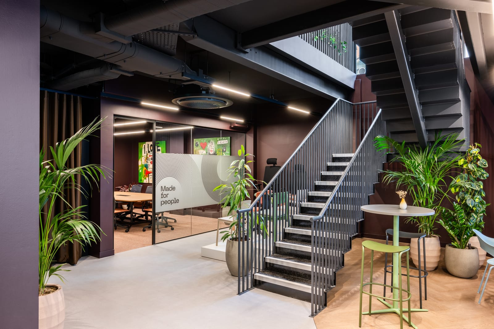 Staircase connecting the floors beside a glass meeting room with frosted branding