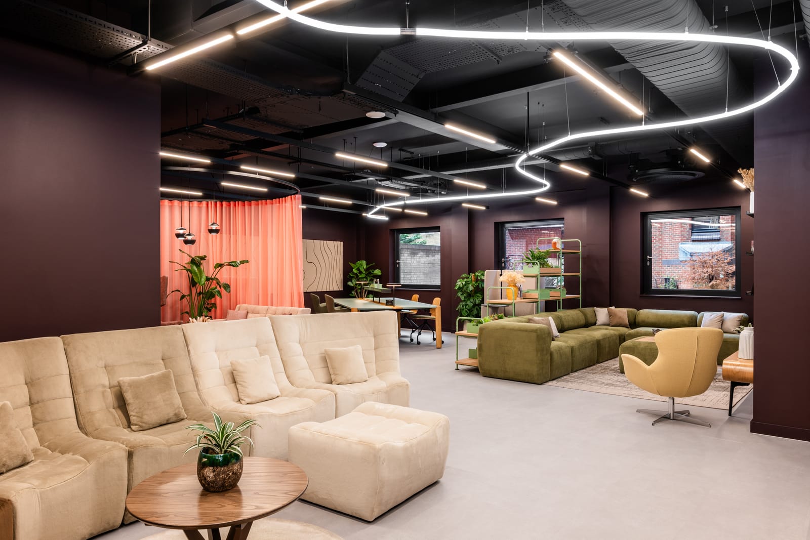 Lower ground lounge with dark plum walls, a looping tubular light and colourful furniture settings