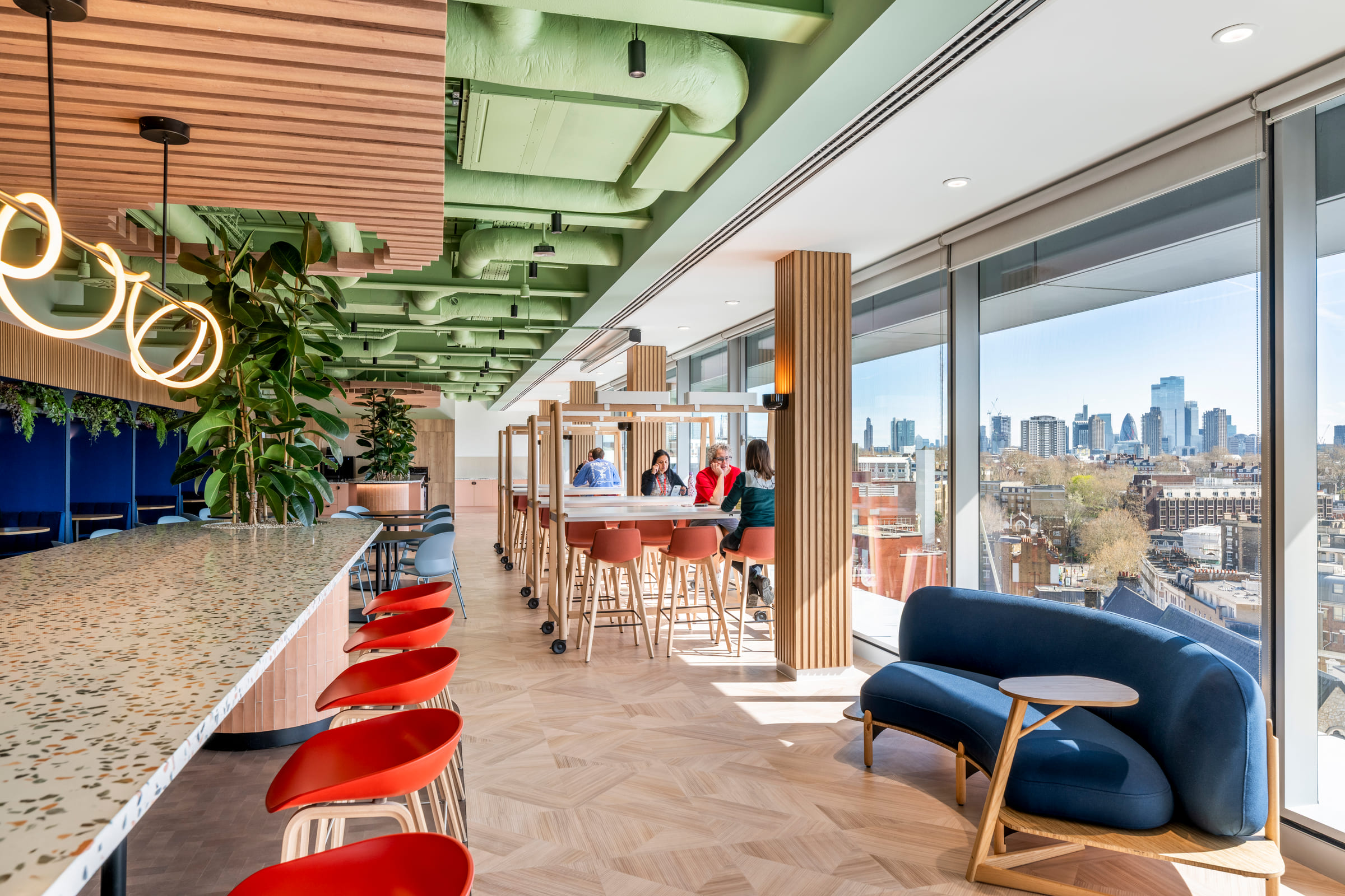 Culture Hub bar with red stools, terrazzo counter, high tables and city skyline view