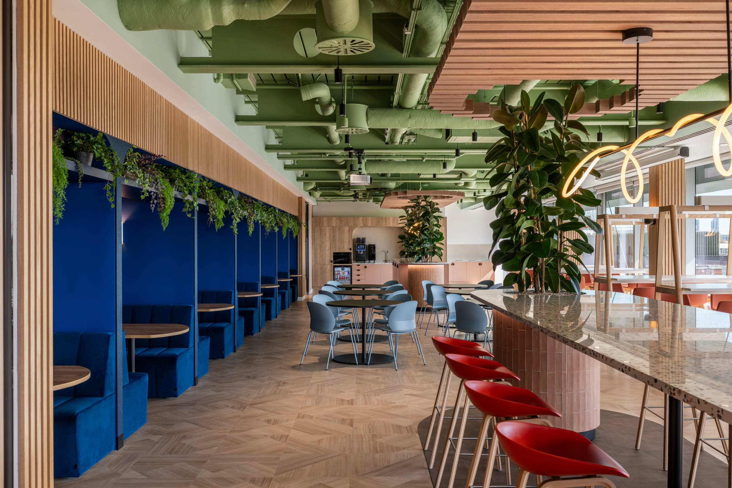Culture Hub booth seating with plants along the blue back wall and herringbone floor