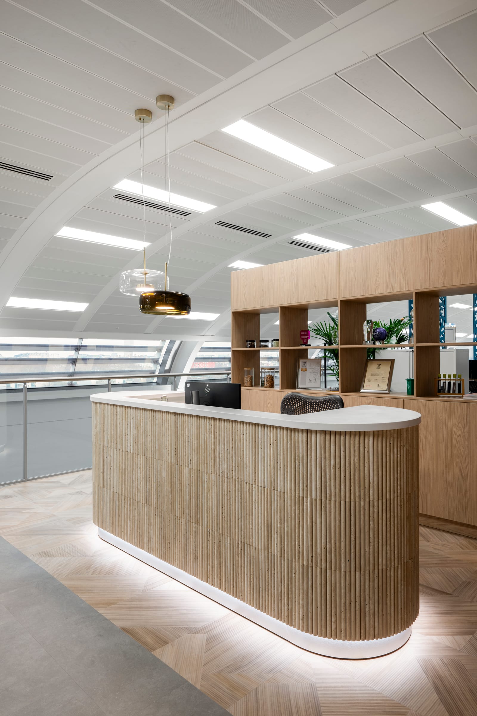 Curved timber reception counter with pendant lighting and herringbone floor