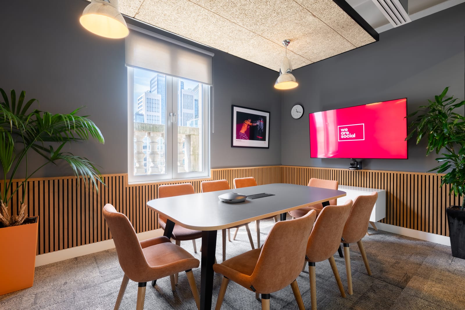 Meeting room with cognac upholstered chairs, timber slat walls and the We Are Social logo on screen