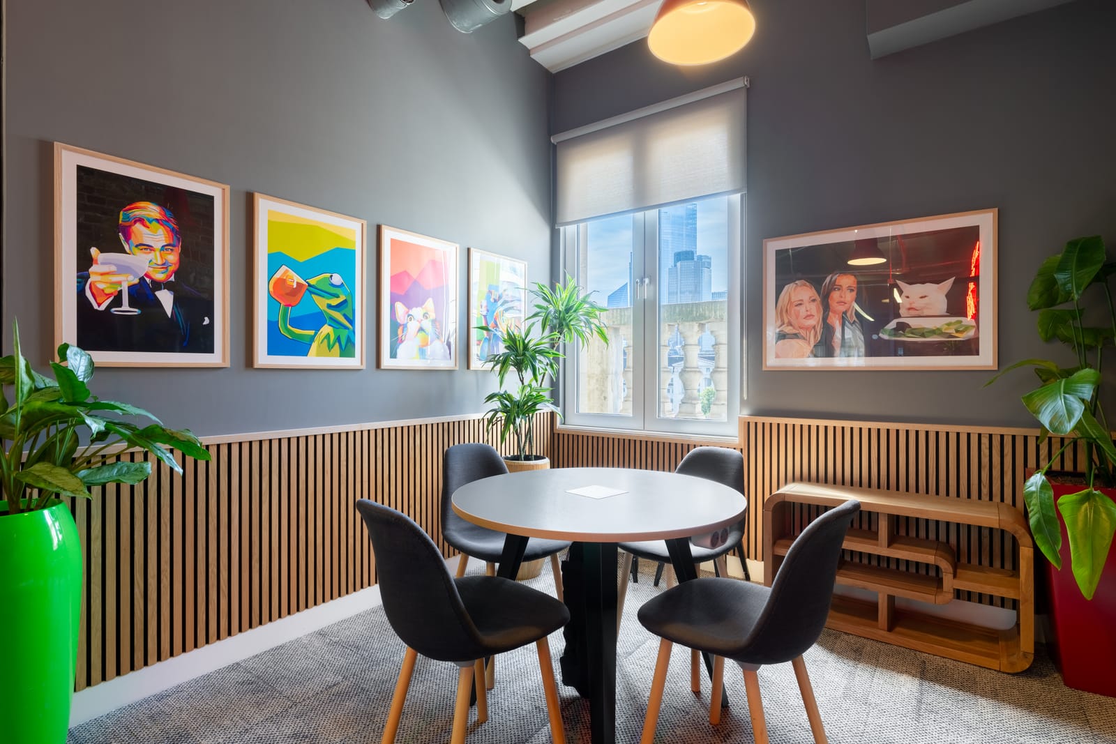 Breakout corner with a gallery wall of pop art prints, timber slat walls and a round table