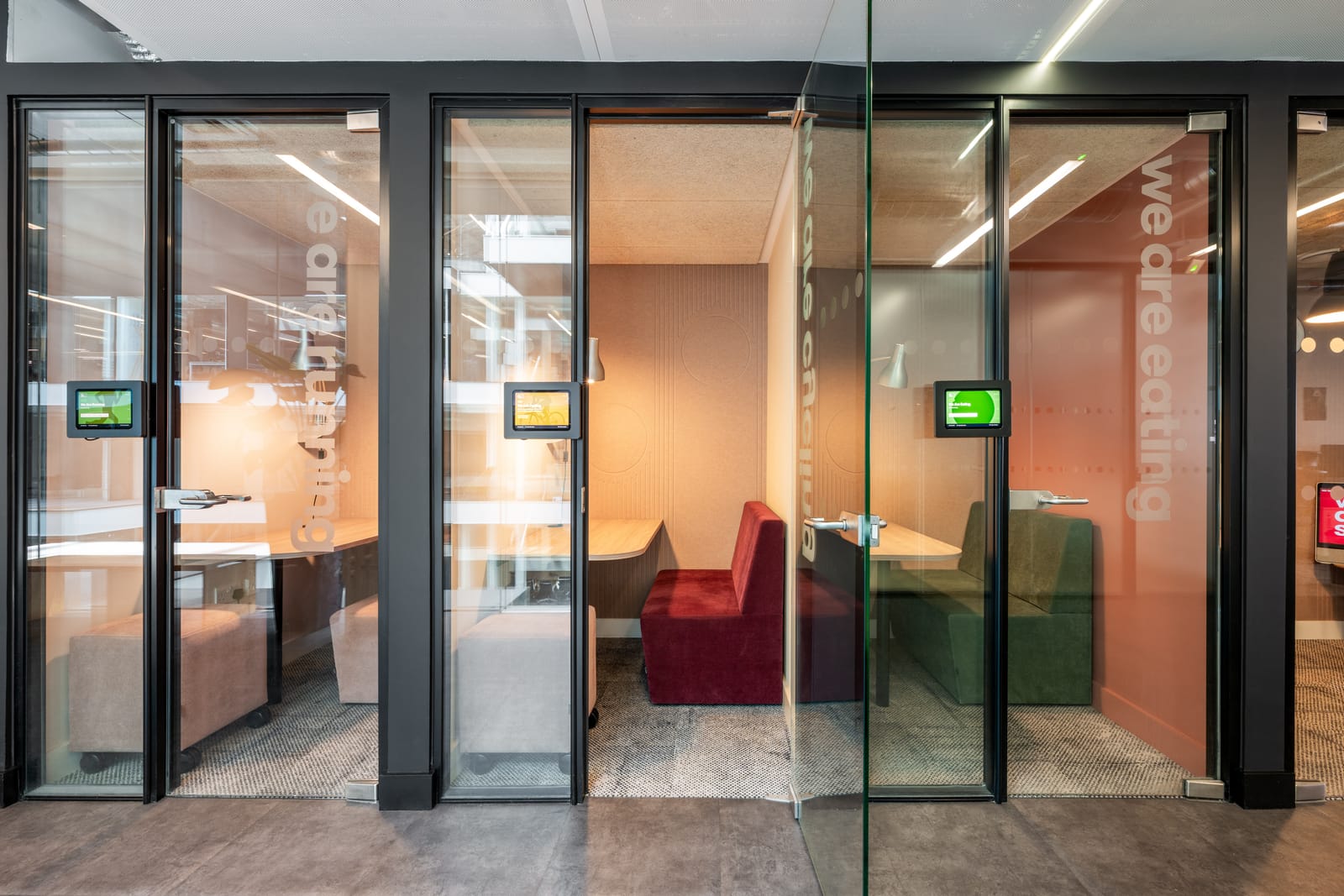 Three glazed focus booths with colourful velvet banquettes and playful manifestations