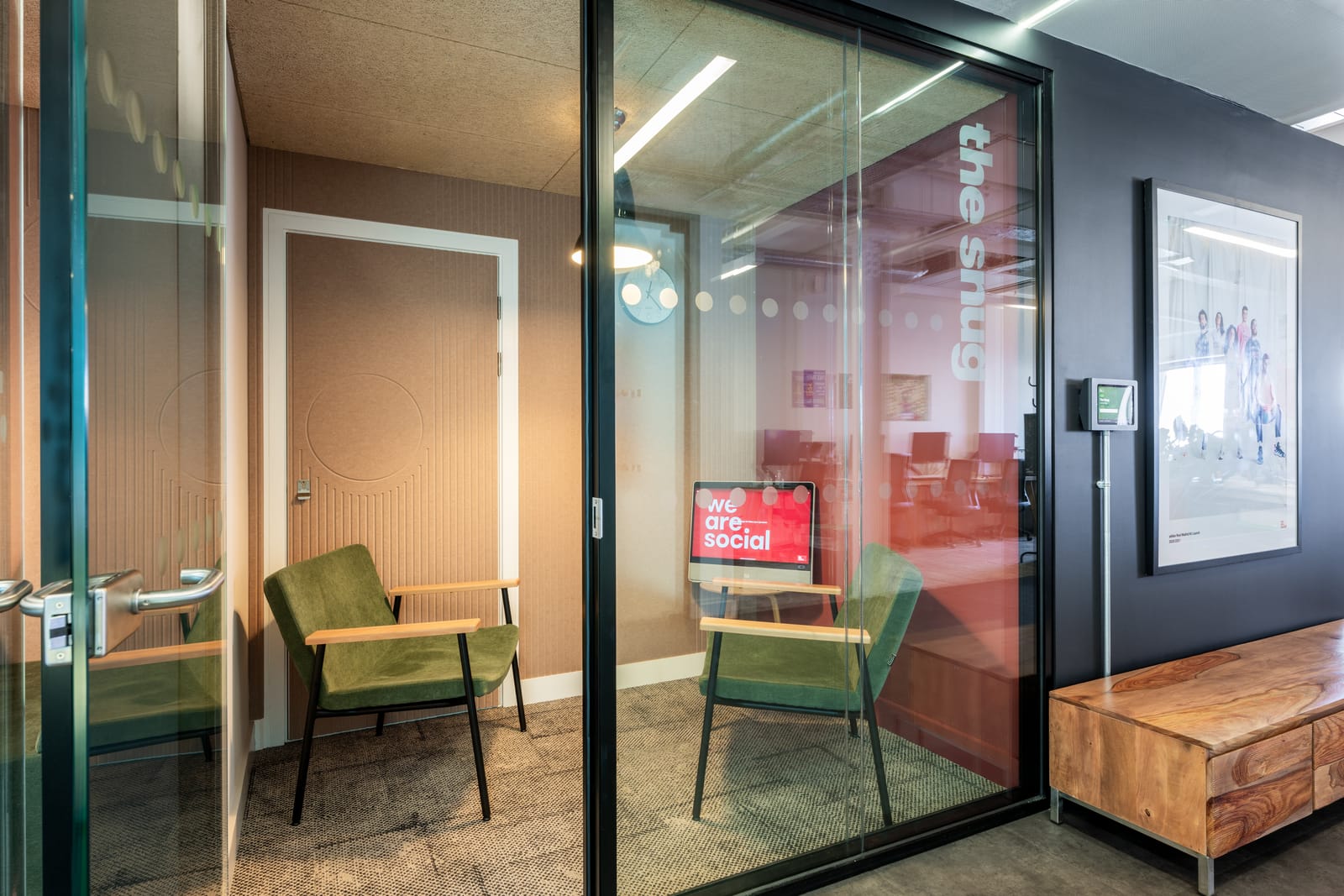 The snug lounge with green velvet armchairs beside a timber media bench